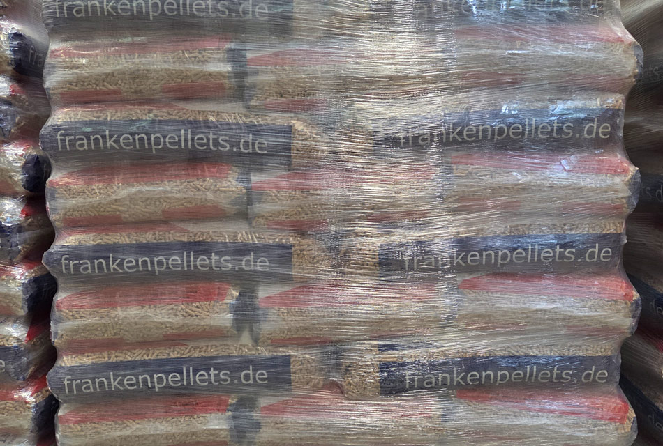 Holzpellets in Foliensäcken mit frankenpellets.de-Schriftzug, liegen aufeinander gestapelt und sind zusätzlich mit Folie umwickelt.