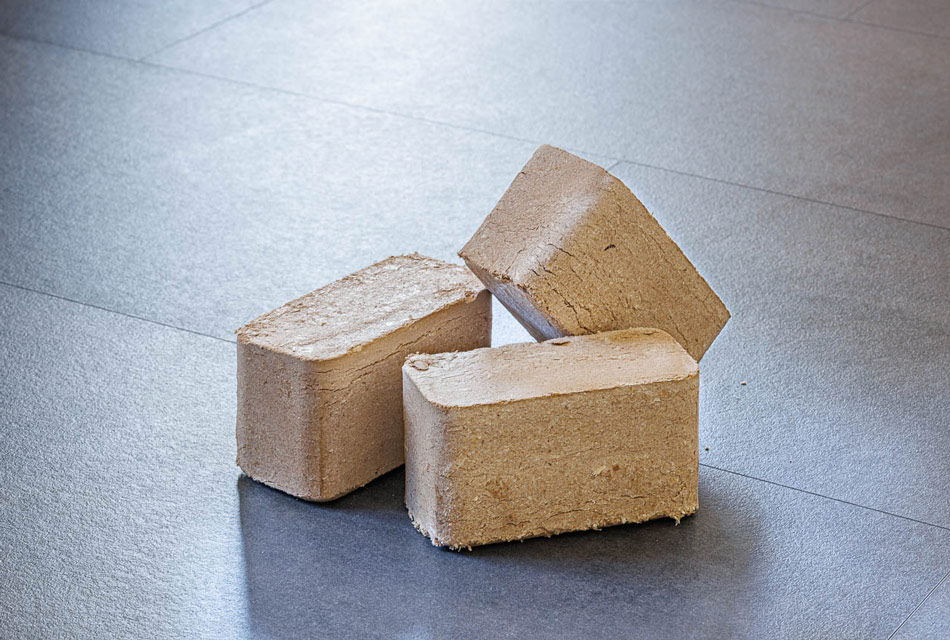 Drei eckige Holzbriketts liegen auf Fliesenboden.